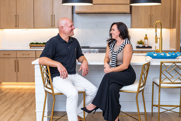 Couple in chairs in a kitchen smiling at one another.