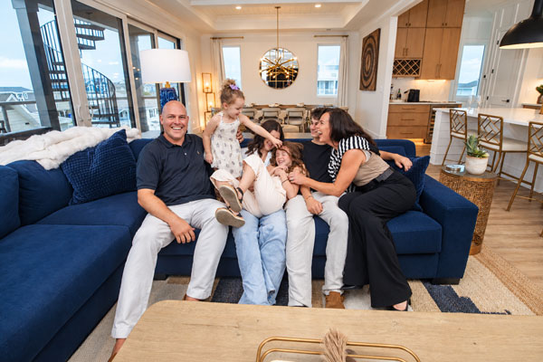 Family on a blue sofa laughing and tickling each other.